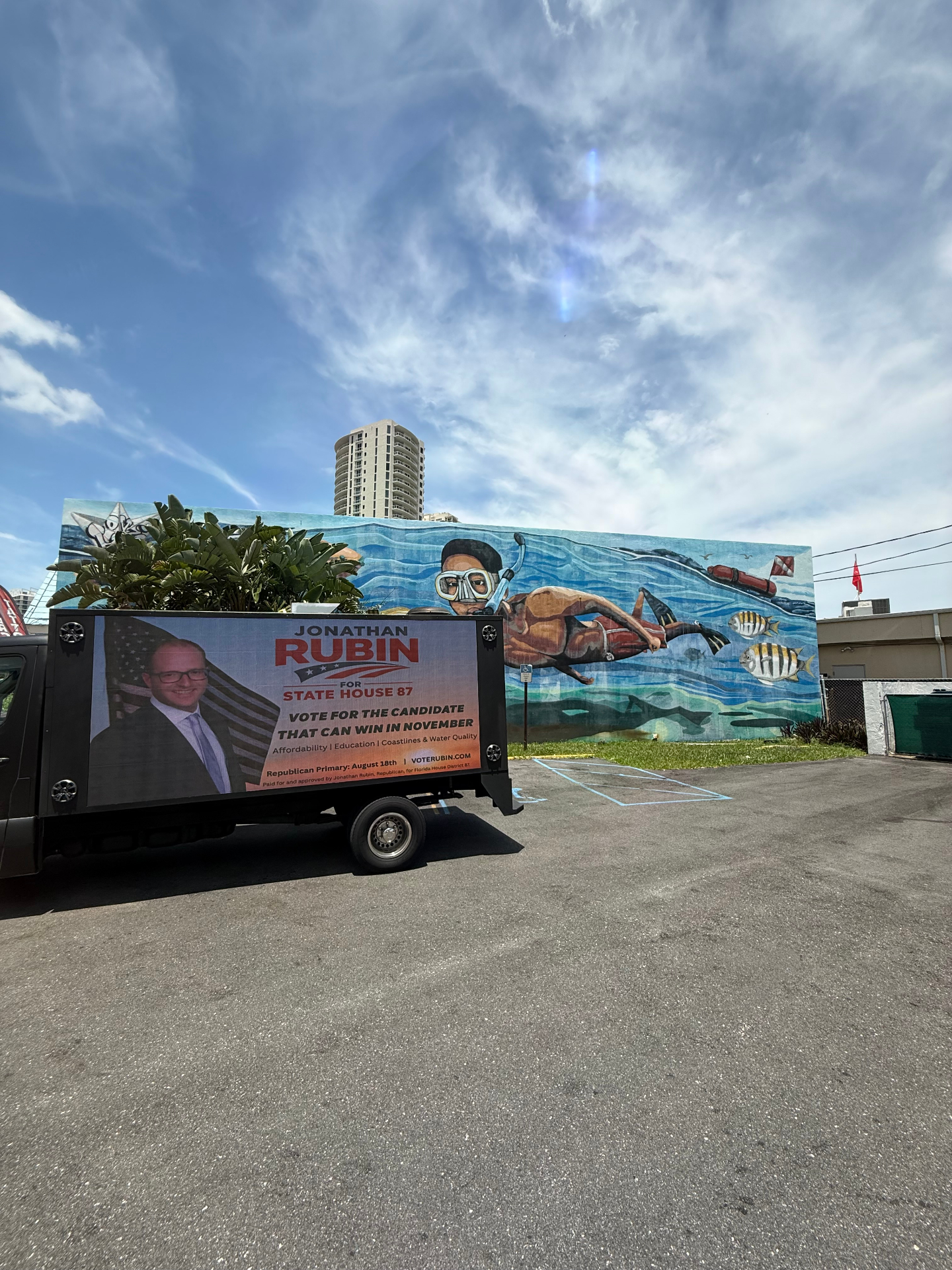 Presidential LED Truck parked beside a public art mural, displaying a candidate campaign creative in bright daylight.